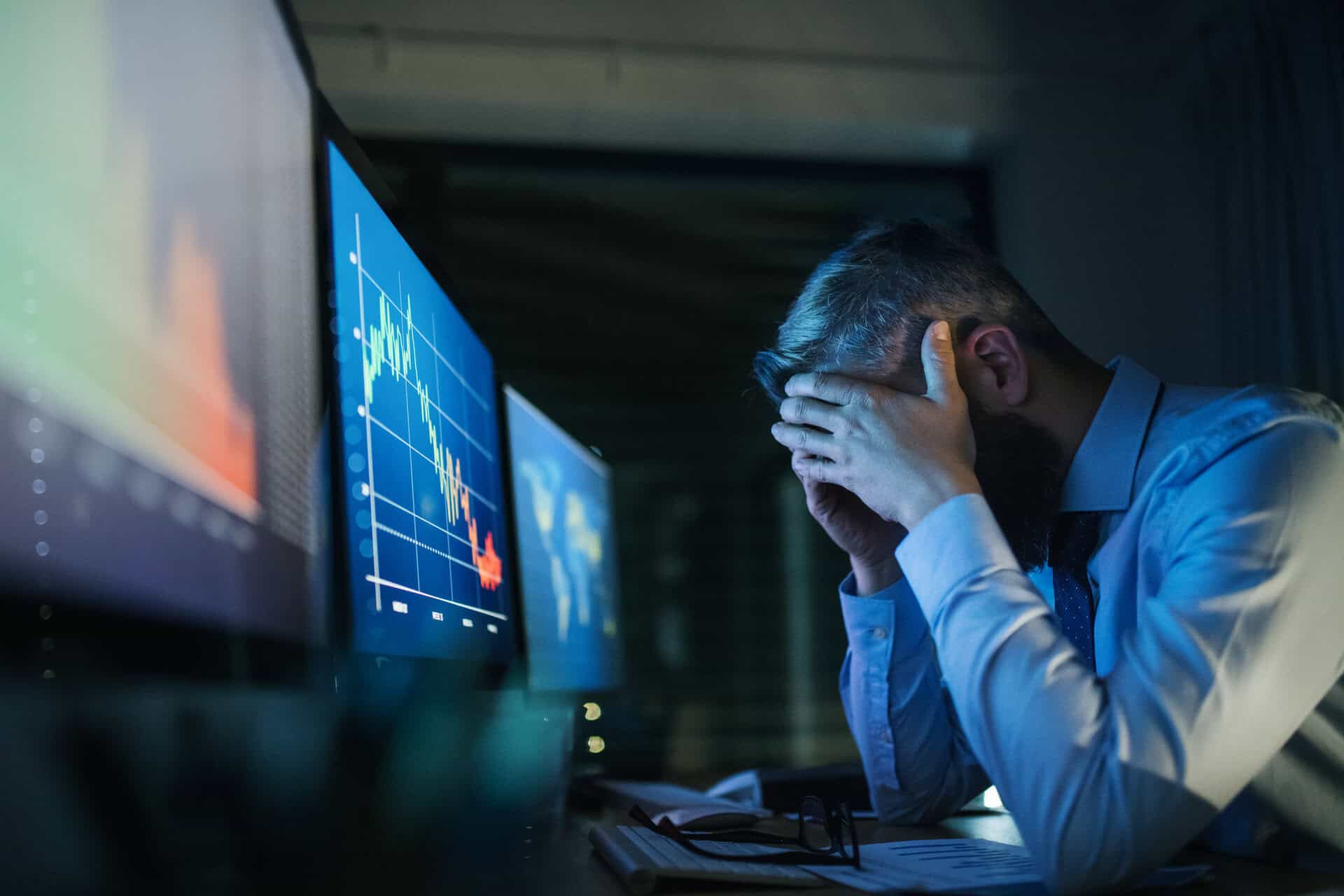 frustrated businessman with computer sitting at desk, working late. financial crisis concept.